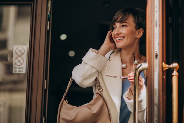 Retrato de mujer joven saliendo de las puertas en algún café