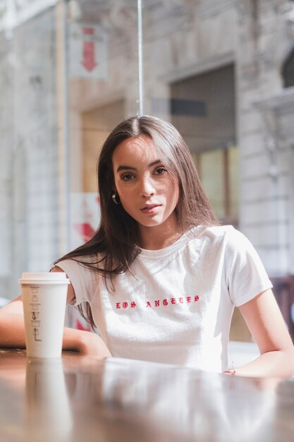 Retrato de una mujer joven sentada en el café mirando a la cámara