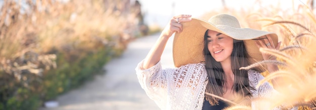 Foto gratuita retrato de una mujer joven sentada en un campo con un sombrero