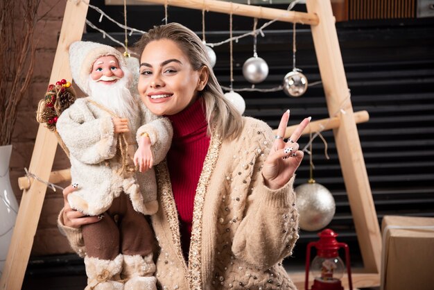 Retrato, de, mujer joven, sentado, en, piso, y, tenencia, un, santa claus, toy., Foto de alta calidad