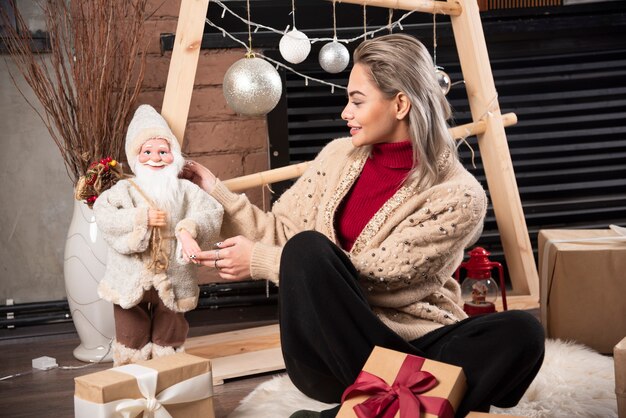 Retrato, de, mujer joven, sentado, y, posar, con, un, santa claus, toy., Foto de alta calidad