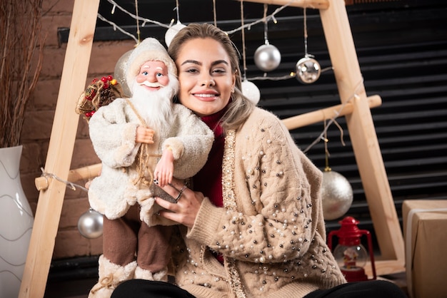 Retrato, de, mujer joven, sentado, y, posar, con, un, santa claus, toy., Foto de alta calidad