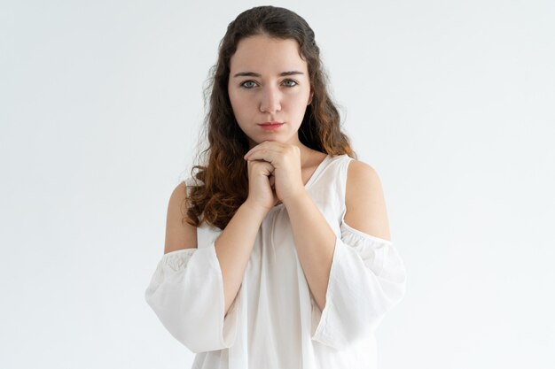 Retrato de mujer joven seria de pie con las manos juntas