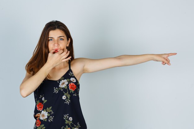 Retrato de mujer joven silbando con los dedos, apuntando hacia el lado