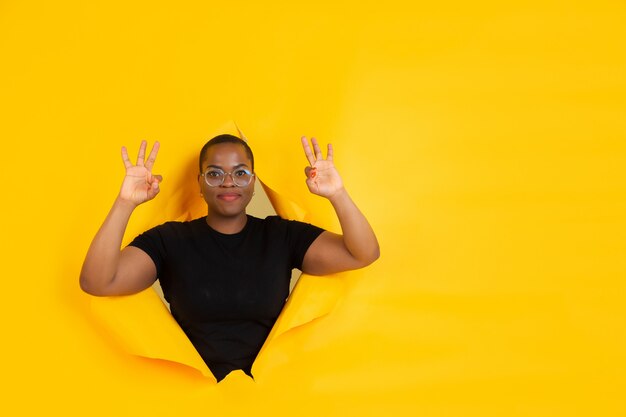 Retrato de mujer joven sobre fondo amarillo roto roto