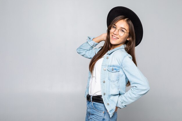 Retrato de mujer joven con sombrero negro aislado en la pared blanca