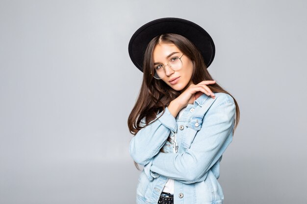 Retrato de mujer joven con sombrero negro aislado en la pared blanca