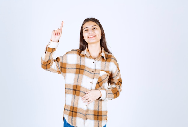 Foto gratuita retrato de mujer joven sonriendo felizmente en la pared blanca.