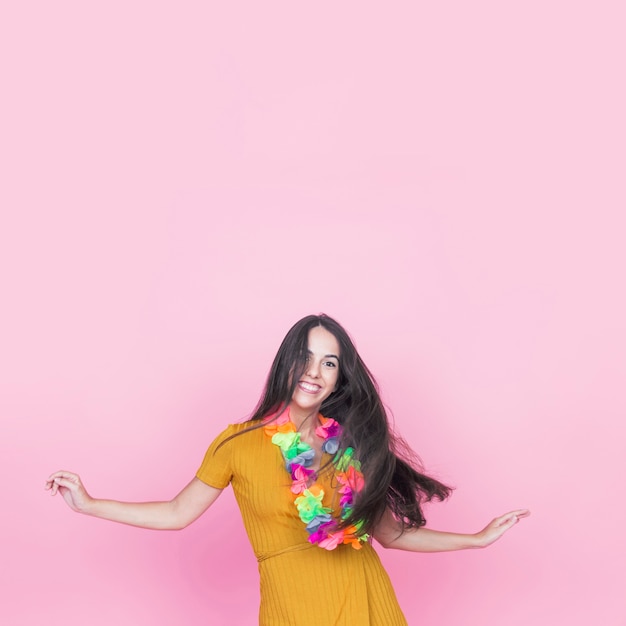 Retrato de mujer joven sonriente bailando sobre fondo rosa