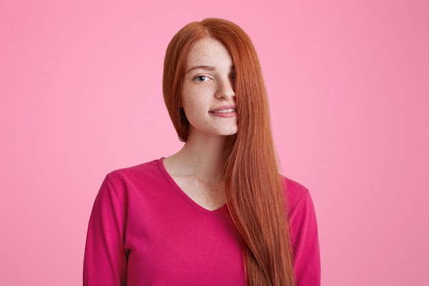 Retrato de mujer joven sonriente complacida con cabello largo y jengibre cubriendo su rostro, modelos para una conocida revista