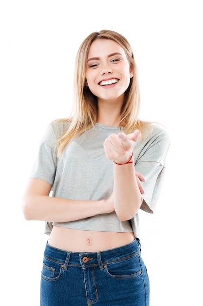 Retrato de una mujer joven sonriente feliz que señala el dedo a la cámara