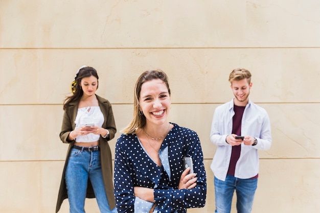 Foto gratuita retrato de mujer joven sonriente frente a hombre y mujer con teléfono móvil