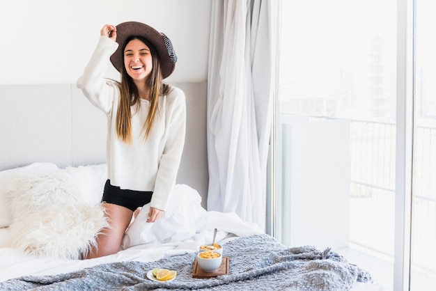 Retrato de una mujer joven sonriente hermosa en cama con el desayuno