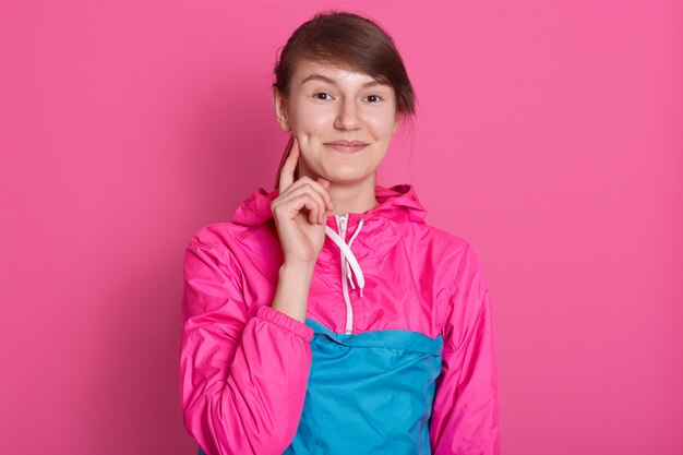 Retrato de mujer joven sonriente mirando directamente a la cámara, atractiva mujer vistiendo camisa deportiva rosa azul