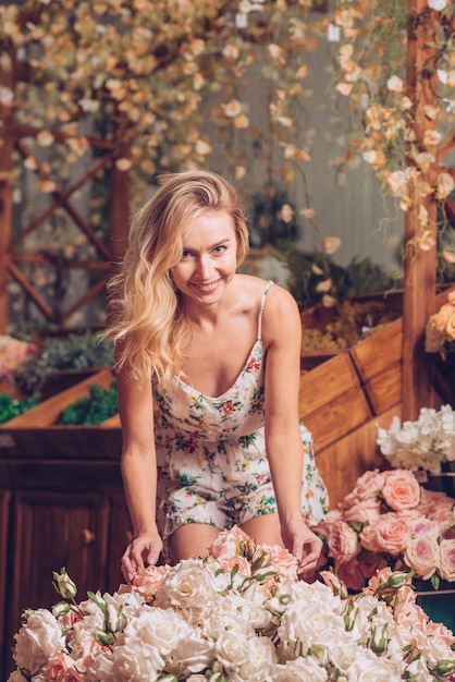 Retrato de una mujer joven sonriente de pie detrás del ramo de rosas