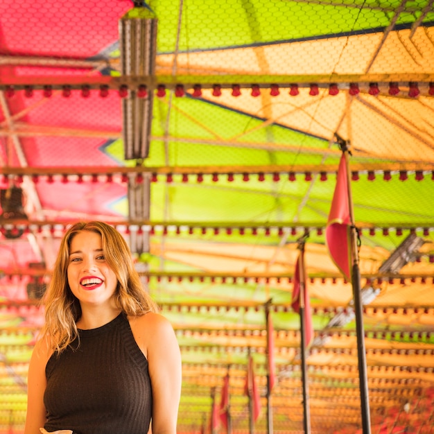 Retrato de mujer joven sonriente de pie bajo la tienda decorativa