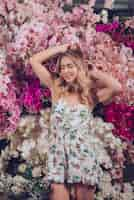 Foto gratuita retrato de una mujer joven sonriente que se coloca delante de las flores plásticas de la orquídea