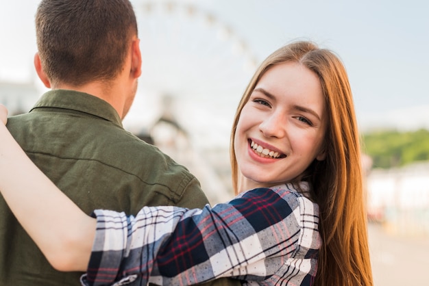 Retrato de la mujer joven sonriente que se coloca con su marido