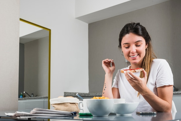 Foto gratuita retrato de una mujer joven sonriente que come el desayuno sano en casa