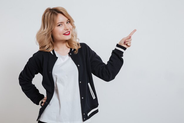 Retrato de una mujer joven sonriente que señala el dedo lejos