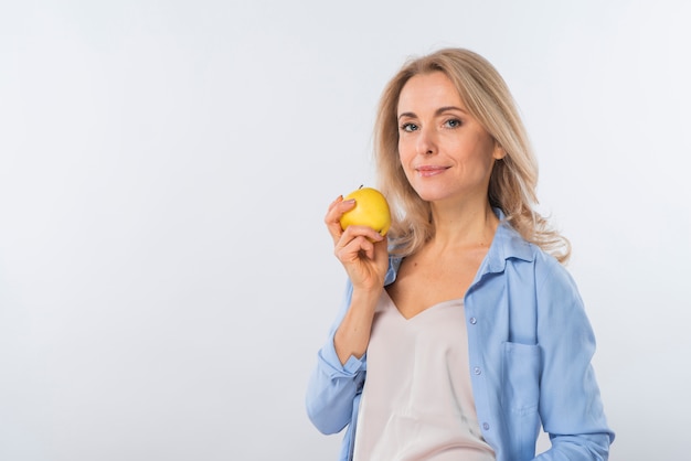 Retrato de una mujer joven sonriente que sostiene la manzana amarilla disponible