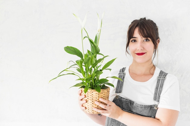 Foto gratuita retrato de una mujer joven sonriente que sostiene la planta en maceta