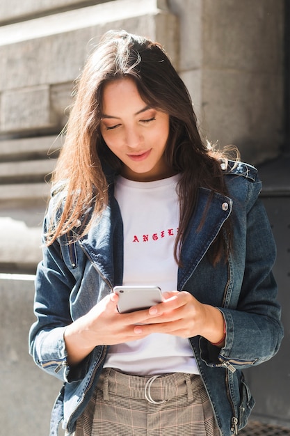 Retrato de una mujer joven sonriente que usa el teléfono móvil