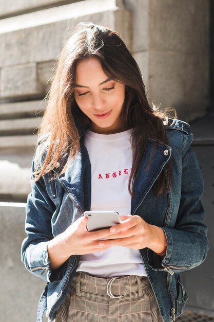 Retrato de una mujer joven sonriente que usa el teléfono móvil