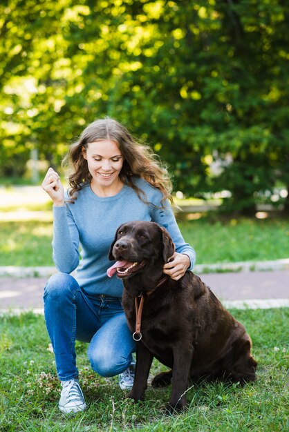 Retrato de una mujer joven sonriente y su perro en el jardín