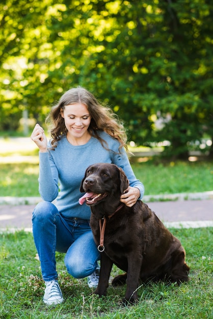 Retrato de una mujer joven sonriente y su perro en el jardín