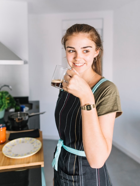 Foto gratuita retrato de mujer joven sonriente con taza de café en la cocina