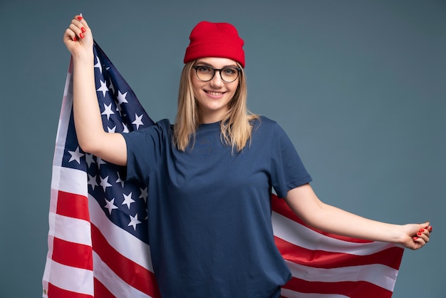 Foto gratuita retrato, de, un, mujer joven, sonriente, y, tenencia, el, bandera estadounidense