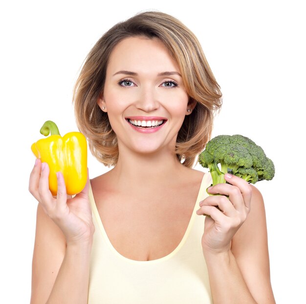 Retrato de una mujer joven sonriente con verduras aislados en blanco.