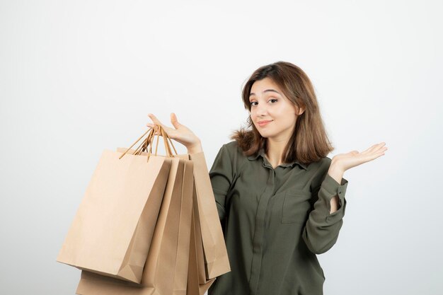 Retrato de mujer joven sosteniendo bolsas de papel artesanal y de pie. foto de alta calidad