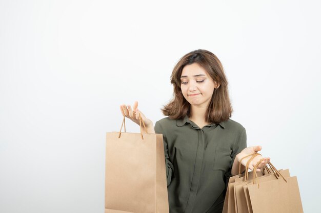 Retrato de mujer joven sosteniendo bolsas de papel artesanal y de pie. foto de alta calidad