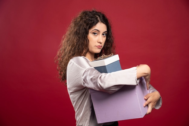 Retrato de mujer joven sosteniendo cajas de regalo con fuerza.