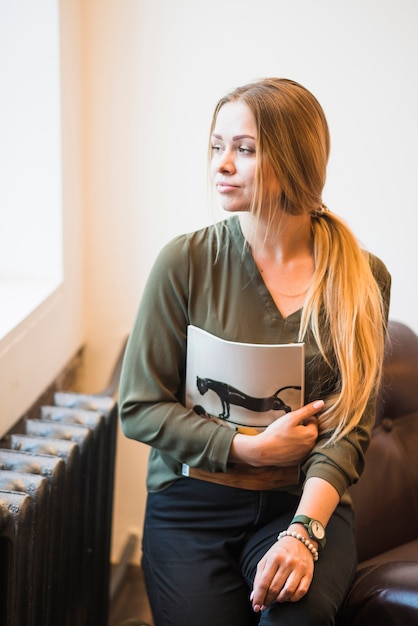 Retrato de mujer joven sosteniendo la revista apartar la mirada