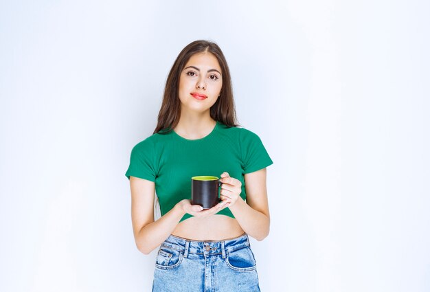 Retrato de mujer joven sosteniendo una taza de té sobre fondo blanco.