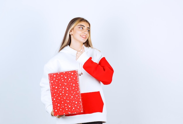 Retrato de mujer joven en suéter caliente con regalo de Navidad mostrando el pulgar hacia arriba