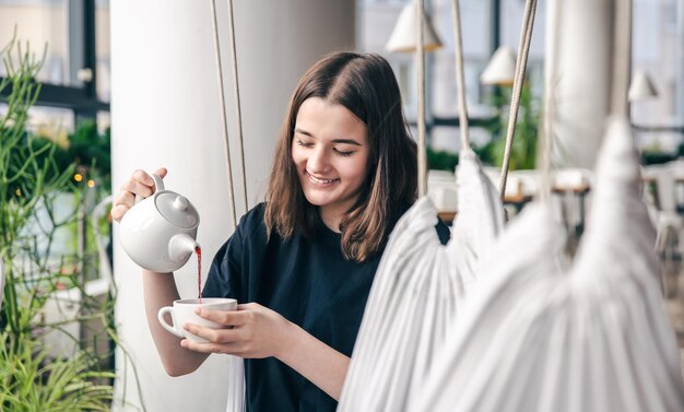 retrato, de, un, mujer joven, con, un, taza de té, en, un, café