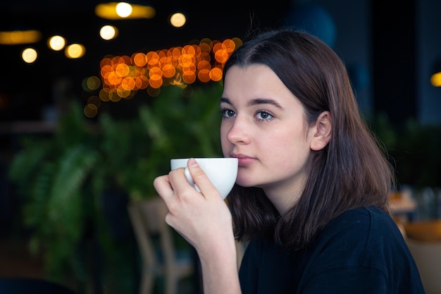 retrato, de, un, mujer joven, con, un, taza de té, en, un, café