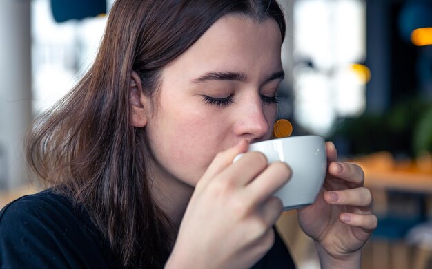 retrato, de, un, mujer joven, con, un, taza de té, en, un, café