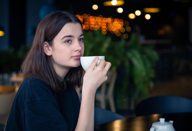 retrato, de, un, mujer joven, con, un, taza de té, en, un, café