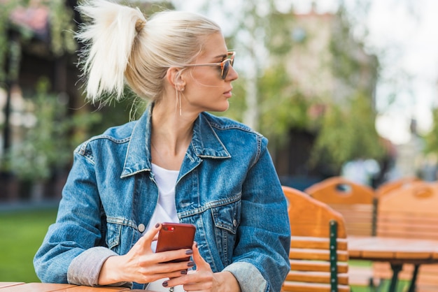 Retrato de una mujer joven con el teléfono móvil que mira lejos