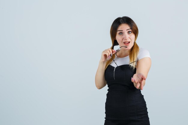 Retrato, de, mujer joven, tenencia, anteojos, mientras, estirar la mano