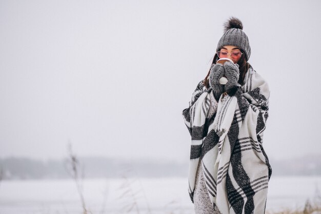 Retrato de mujer joven tomando café en un parque de invierno