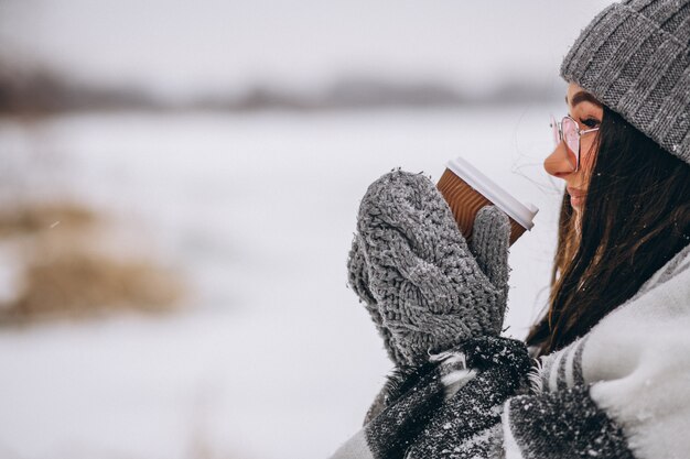 Retrato de mujer joven tomando café en un parque de invierno