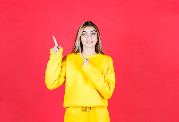 Retrato de mujer joven en traje amarillo apuntando a algún lugar