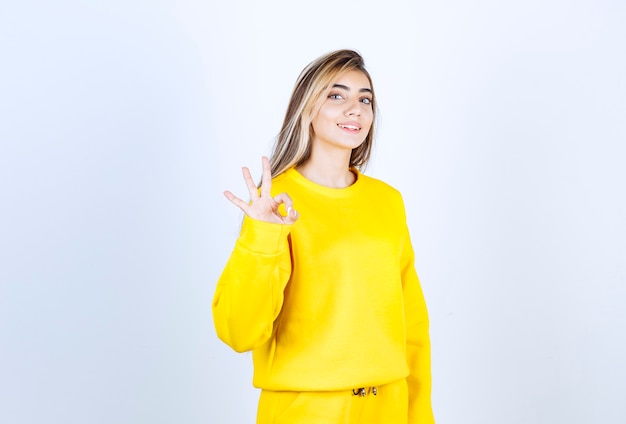 Retrato de mujer joven en traje amarillo de pie siendo positivo