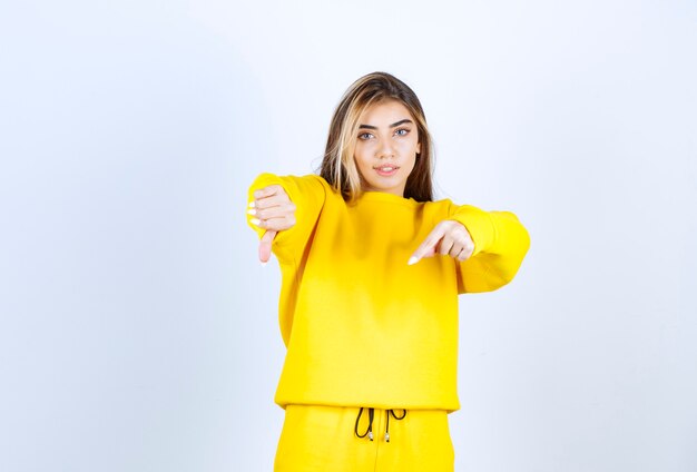 Retrato de mujer joven en traje amarillo de pie siendo positivo